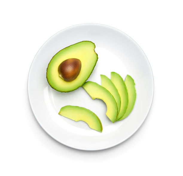 将牛油果切成半片放在盘子上，放在白色背景上，俯视图图片下载