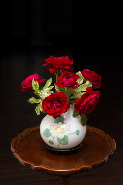 鲜切的红玫瑰插在黑色背景的古董花瓶里图片下载