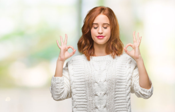 年轻美丽的女人在孤立的背景穿着冬季毛衣放松和微笑，闭上眼睛做冥想手势与手指。瑜伽的概念。图片下载