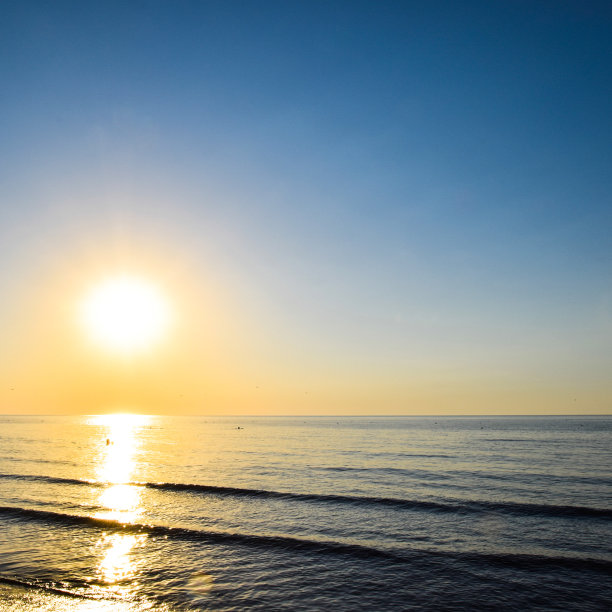 海上日落。傍晚日落时，人们在海里洗澡。图片下载