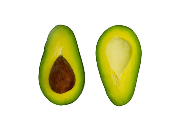 新鲜的牛油果切成两半，单独平放在白色的表面上图片下载