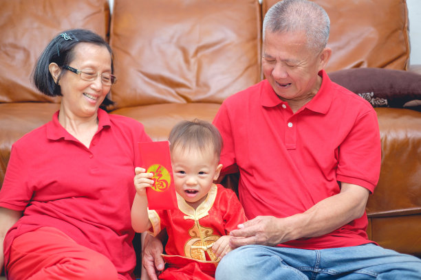 亚洲的祖父母给他们的孙子红包，可爱的蹒跚学步的小男孩穿着红色的中国衣服拿着红包图片下载