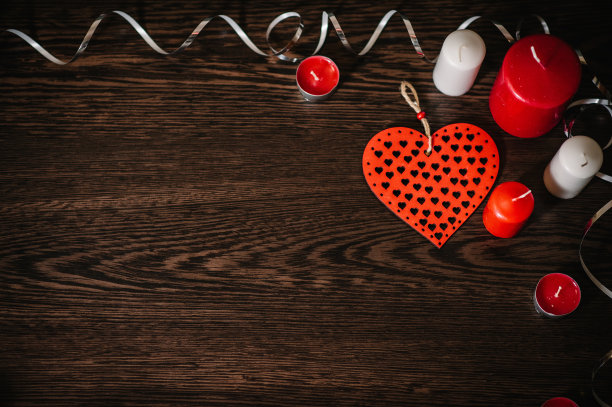 情人节贺卡快乐。一个浪漫的概念假日，蜡烛，丝带，装饰红心在棕色的木制背景。爱组成。空间的文本。平的。前视图。图片下载