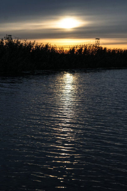 日落在河上，湖上。阳光在水中的反射就像在镜子里一样。景观背景。库存图片图片下载