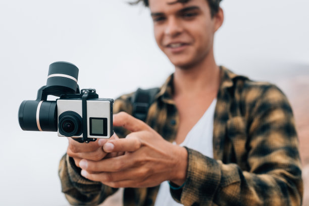一个年轻帅气的小伙子站在户外用摄像机拍摄视频。图片下载