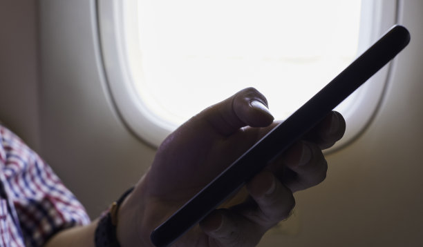 在飞机内靠近窗户的地方，一只手拿着手机图片下载