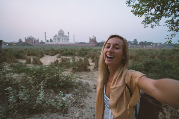 日落时分，印度阿格拉，游客在著名的泰姬陵用手机自拍。亚洲人旅游概念图片下载