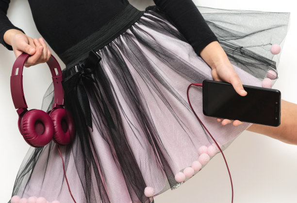 一个拿着智能手机和耳机的女孩。图片下载