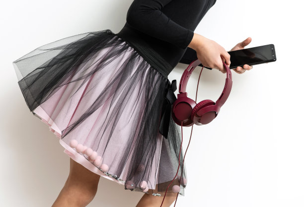 一个拿着智能手机和耳机的女孩。图片下载