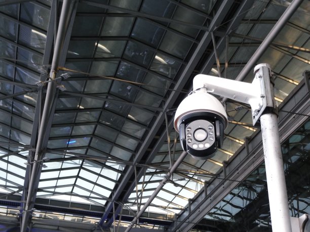 闭路电视安全摄像头在高高的金属柱上，对着高高的天花板透明的屋顶图片下载