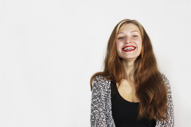 一个留着棕色长发，涂着红色口红的女孩微笑着看着镜头图片下载