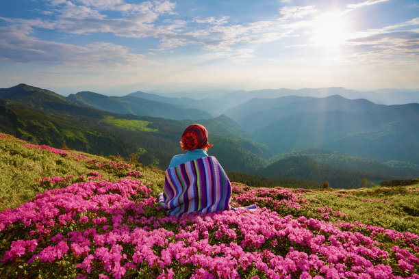 草地上看山景的少女与粉色杜鹃花素材图片