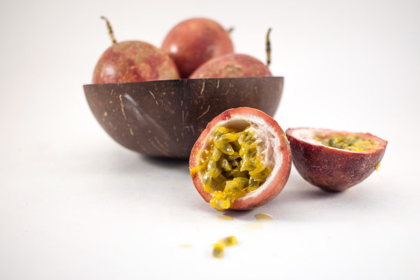 百香果孤立。整个西番莲果放在一个椰子碗里，半颗maracuya孤立在白色背景上图片下载