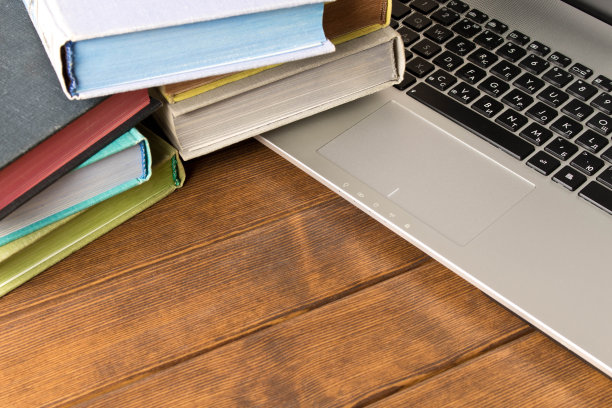 书和笔记本放在木桌上。从书本或互联网上学习的概念图片下载