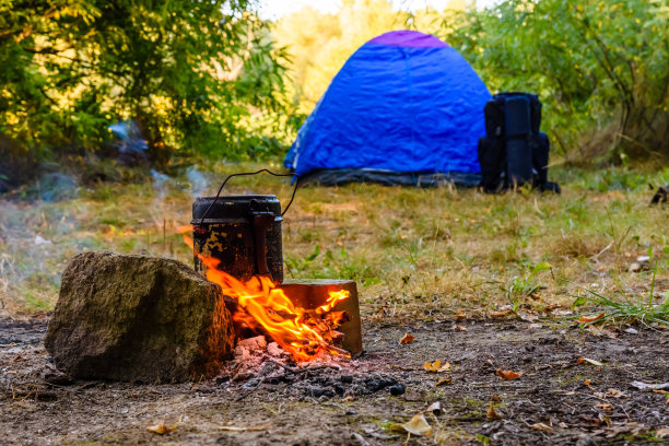 用水壶在篝火上煮食物。帐篷的背景图片下载