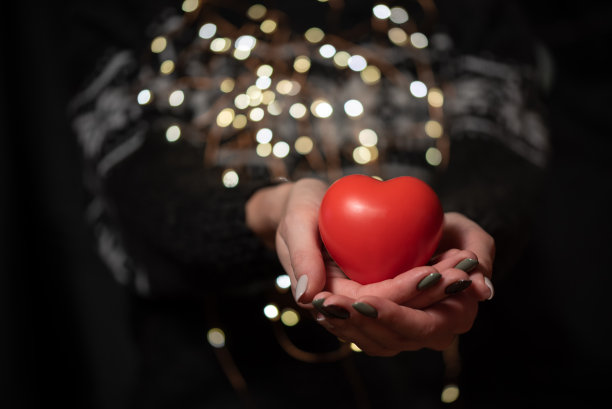 穿着深色冬季毛衣的女孩手里拿着一颗红色的心图片下载