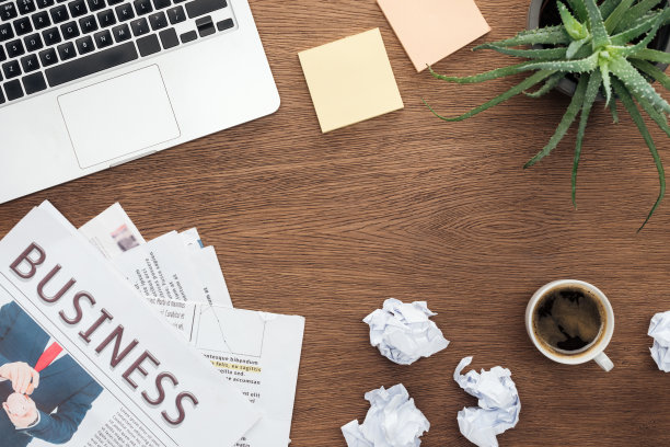 俯视图笔记本电脑，商业报纸，盆栽植物和一杯咖啡在木制桌面上图片下载