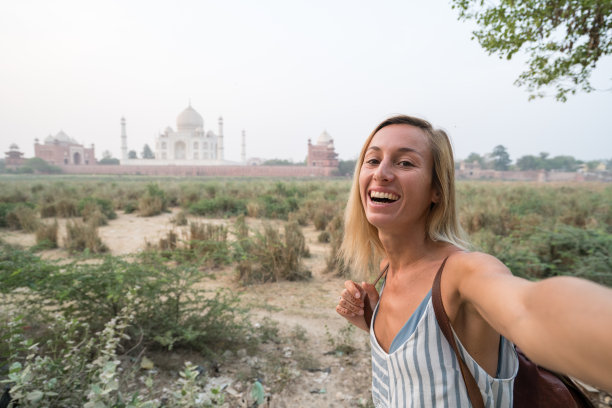 日落时分，印度阿格拉，游客在著名的泰姬陵用手机自拍。亚洲人旅游概念图片下载