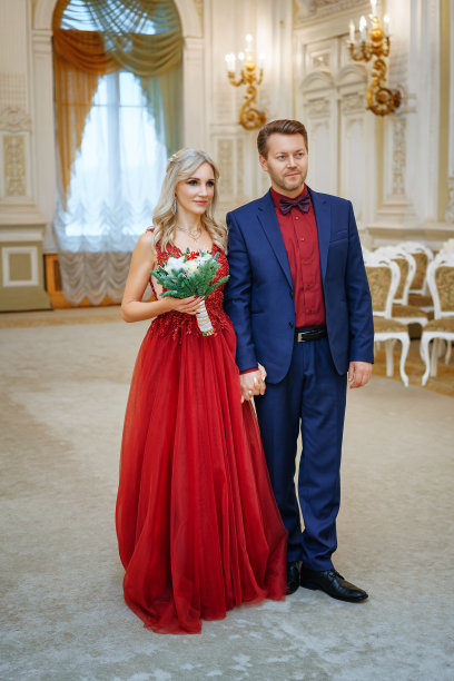 一个穿着红裙子的漂亮女人和一个男人站在一起，新娘和新郎，幸福的新婚夫妇。图片下载