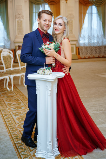 一个穿着红裙子的漂亮女人和一个男人站在一起，新娘和新郎，幸福的新婚夫妇。图片下载