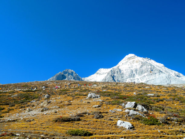 白雪覆盖的山峰和旅行者徒步旅行的景色图片下载
