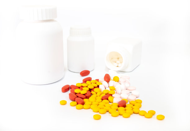 红色、黄色、粉色药片和白色药瓶放在白色背景上，医学概念图片下载