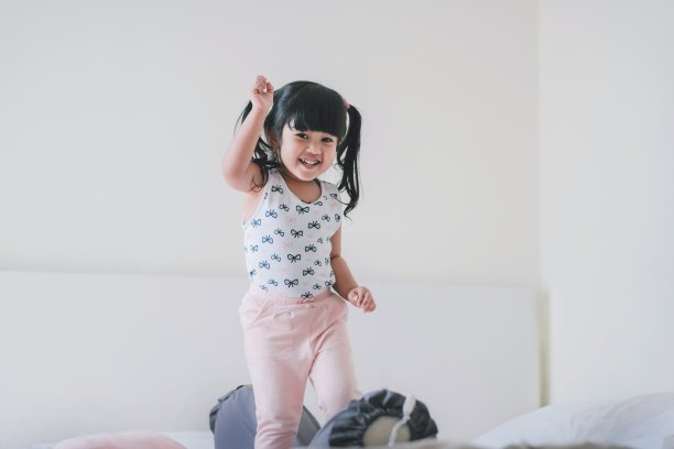 快乐可爱的孩子肖像。一个三岁的女孩在卧室里的幸福时刻，微笑着看着相机图片下载