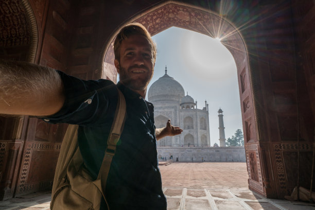印度阿格拉，一名男性游客在日落时分用手机自拍著名的泰姬陵。亚洲人旅游概念图片下载