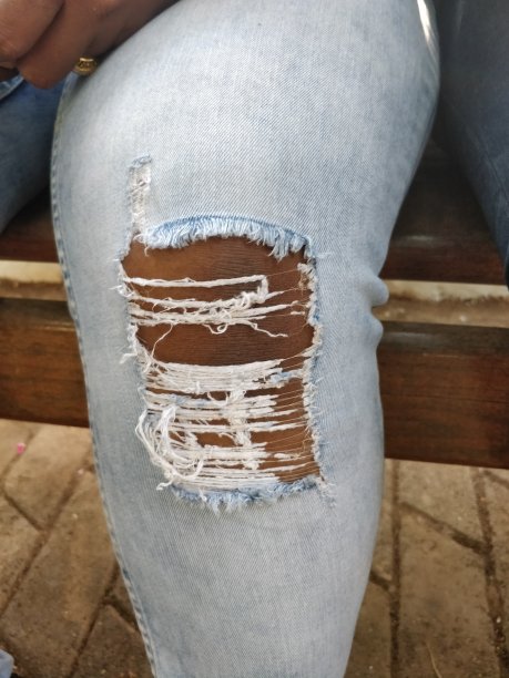 穿在膝盖上的时尚破洞牛仔裤图片下载