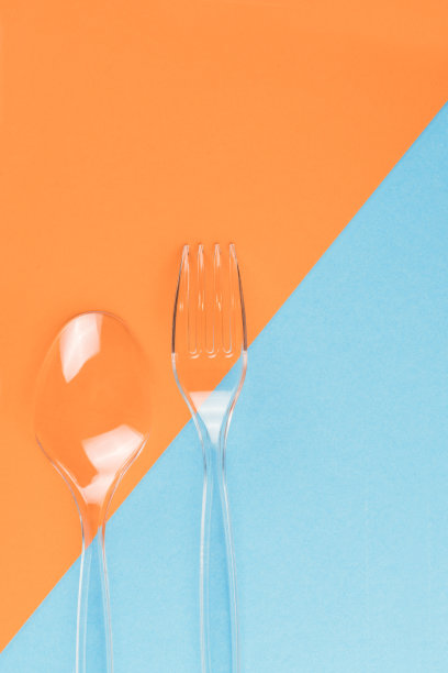 透明塑料叉子和勺子在蓝色和橙色的背景图片下载