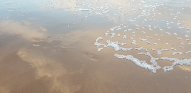 白色的泡沫到达沙滩图片下载