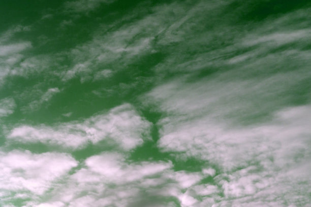 蓬松的云朵在天空中，绿色和黄色的分裂色调交叉处理。图片下载