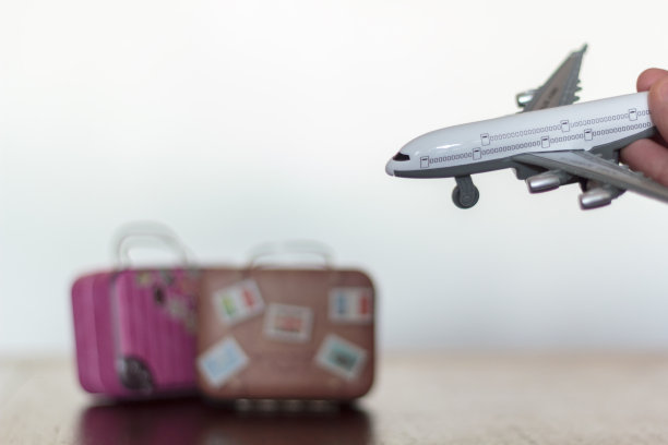 手里拿着飞机，背景是旅行箱图片下载