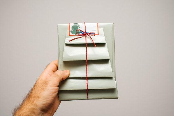 男人拿着用绿色光纸包裹的节日礼物图片下载