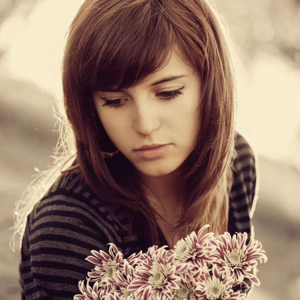 悲伤的年轻女子带着花在户外做白日梦图片下载