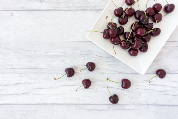 樱桃在一个盘子和木面板背景图片下载