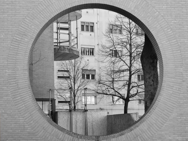 从砖墙的一个圆形开口看到的城市公寓图片下载