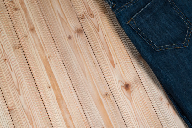 磨损牛仔裤或蓝色牛仔裤牛仔收集粗糙的木制桌子背景与拷贝空间，旧的时尚概念。图片下载