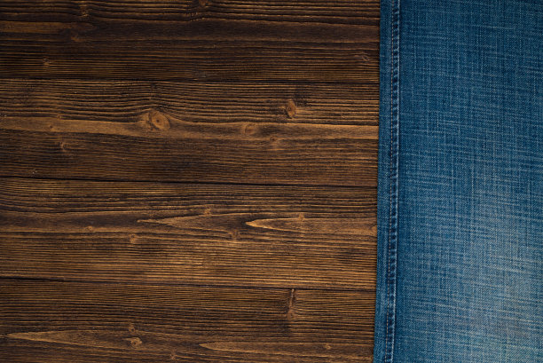 磨损牛仔裤或蓝色牛仔裤牛仔收集在粗糙的深色木制桌子背景，顶部视图与拷贝空间，旧的时尚概念。图片下载