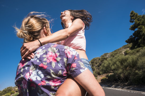 幸福和快乐的概念，年轻的白人有吸引力的夫妇。男人把女孩背在背上，转身逗她笑，玩得很开心。美人儿享受户外休闲活动图片下载