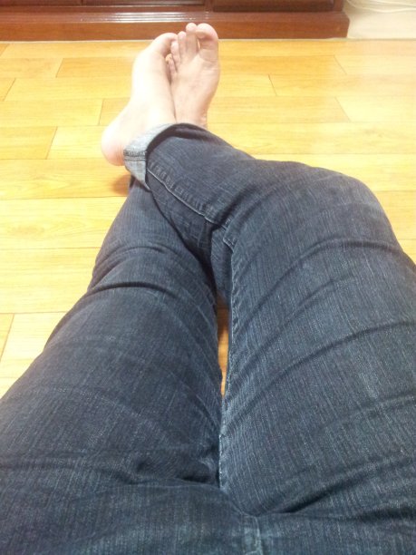 光脚男人放松在木地板与蓝色牛仔裤图片下载