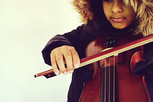 从正面拍摄的水平照片，一个男孩正在拉着弦乐器，小提琴图片下载