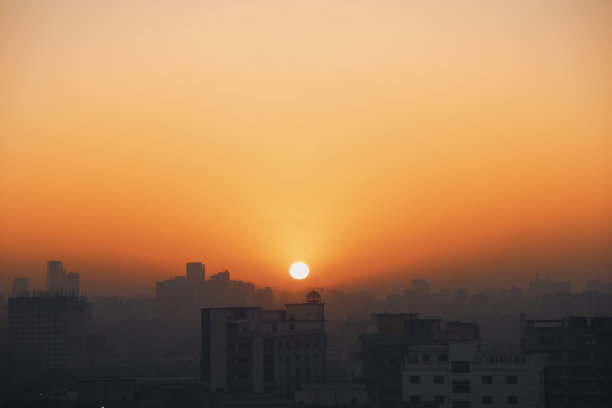 太阳正冉冉升起在一个人口稠密的高楼城市上空图片下载