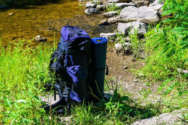 旅游背包在河边的森林图片下载