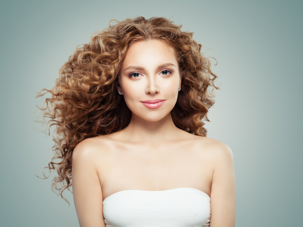 微笑的女人肖像。灰色背景下的红发女孩有着健康的长卷发图片下载