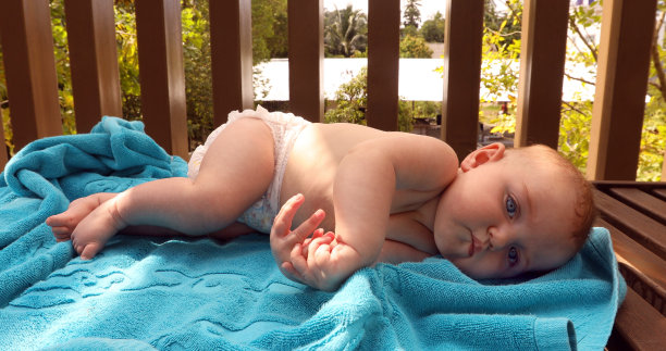 滑稽的婴儿躺在婴儿床的毛巾上图片下载