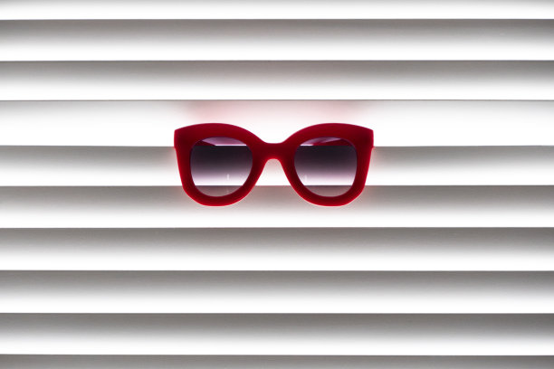 红色的太阳眼镜戴在白色的百叶窗上图片下载