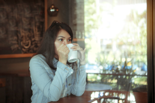一个亚洲漂亮女人在室内咖啡馆喝咖啡图片下载