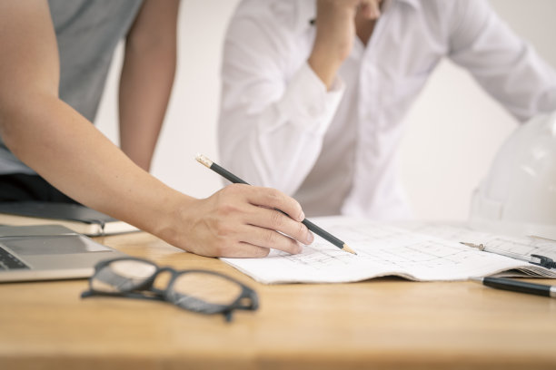 建筑师团队在办公室讨论房屋或建筑物的问题，平面图仅为库存照片而伪造。图片下载