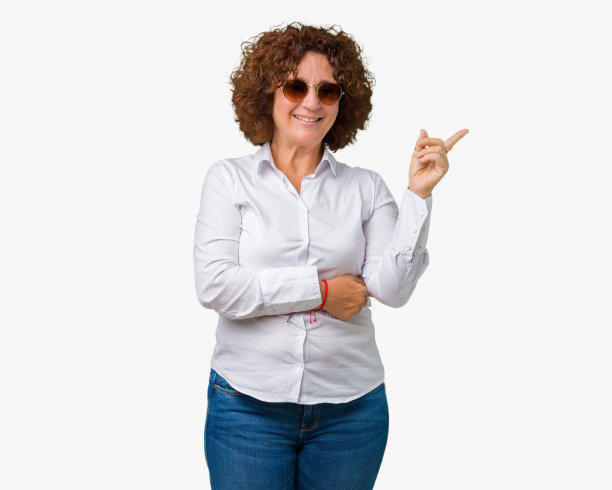 美丽的中年高级商务女性戴太阳镜在孤立的背景与一个大大的微笑在脸上，指着与手和手指在一边看着相机。图片下载